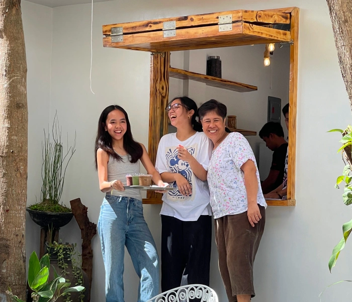 three people smiling holding coffee