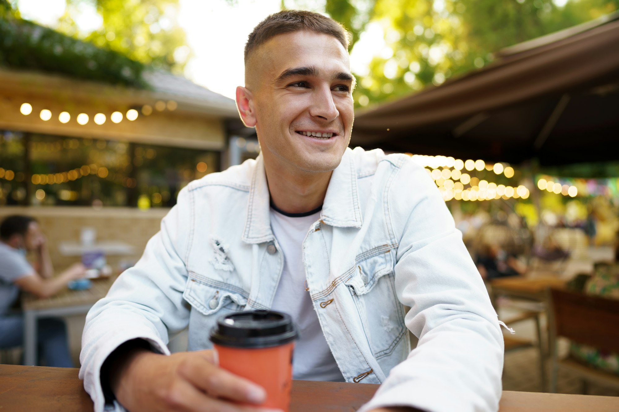 Young man with cup of coffee sitting in outdoor cafe